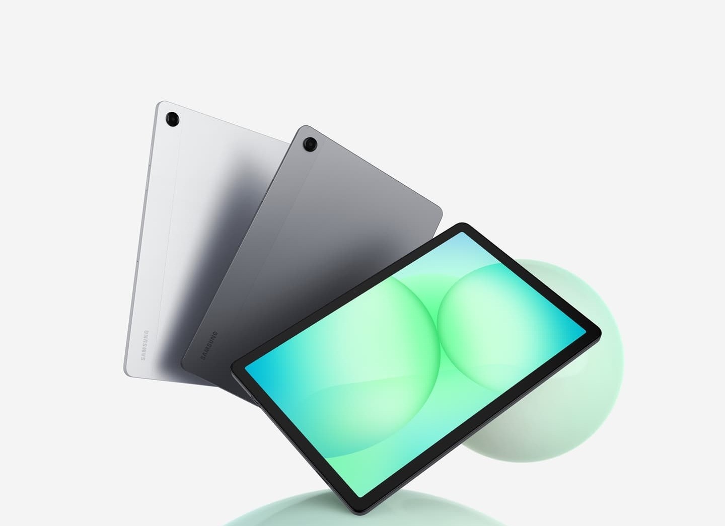 Three Galaxy Tab A11+ tablets are arranged in a fan layout. The first two on the left show their backs in silver and gray, while the front-facing tablet displays a greenish circular patterned graphic on its screen. Above the tablets, the text reads 'Galaxy Tab A11+'.