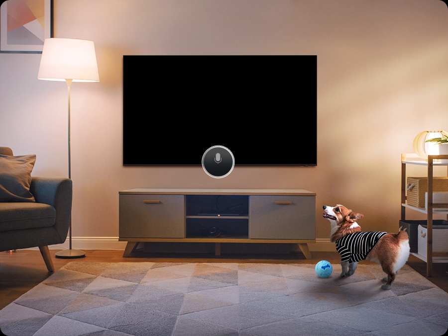 A dog barks in a living room as a Samsung TV sits turned off at the center of the space. The TV detects the sound through the Pet Care function and automatically turns on, playing a calming video of a dog at play.