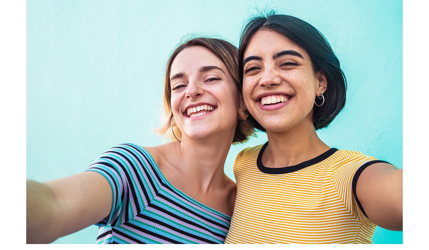 Two women smiling while taking a selfie together using Galaxy A27 5G's 12 MP Front Camera. The selfie looks clear and natural with lively colors, sharp details and optimal exposure.