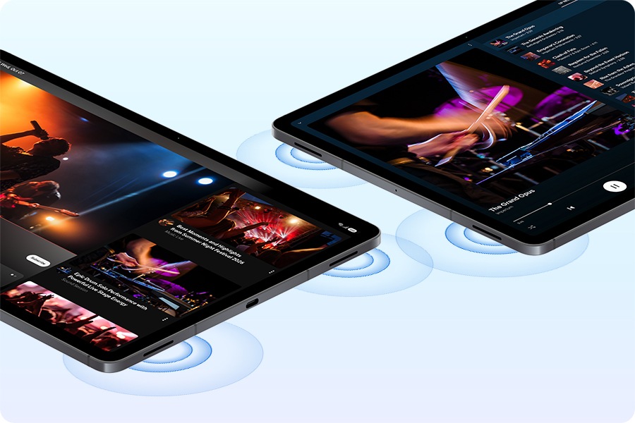 Two Galaxy Tab S12 Plus devices placed lying down next to each other with videos of live concert performances playing in YouTube app on one device and YouTube Music app on the other. Sound waves are coming from the 4-channel audio system on both devices.