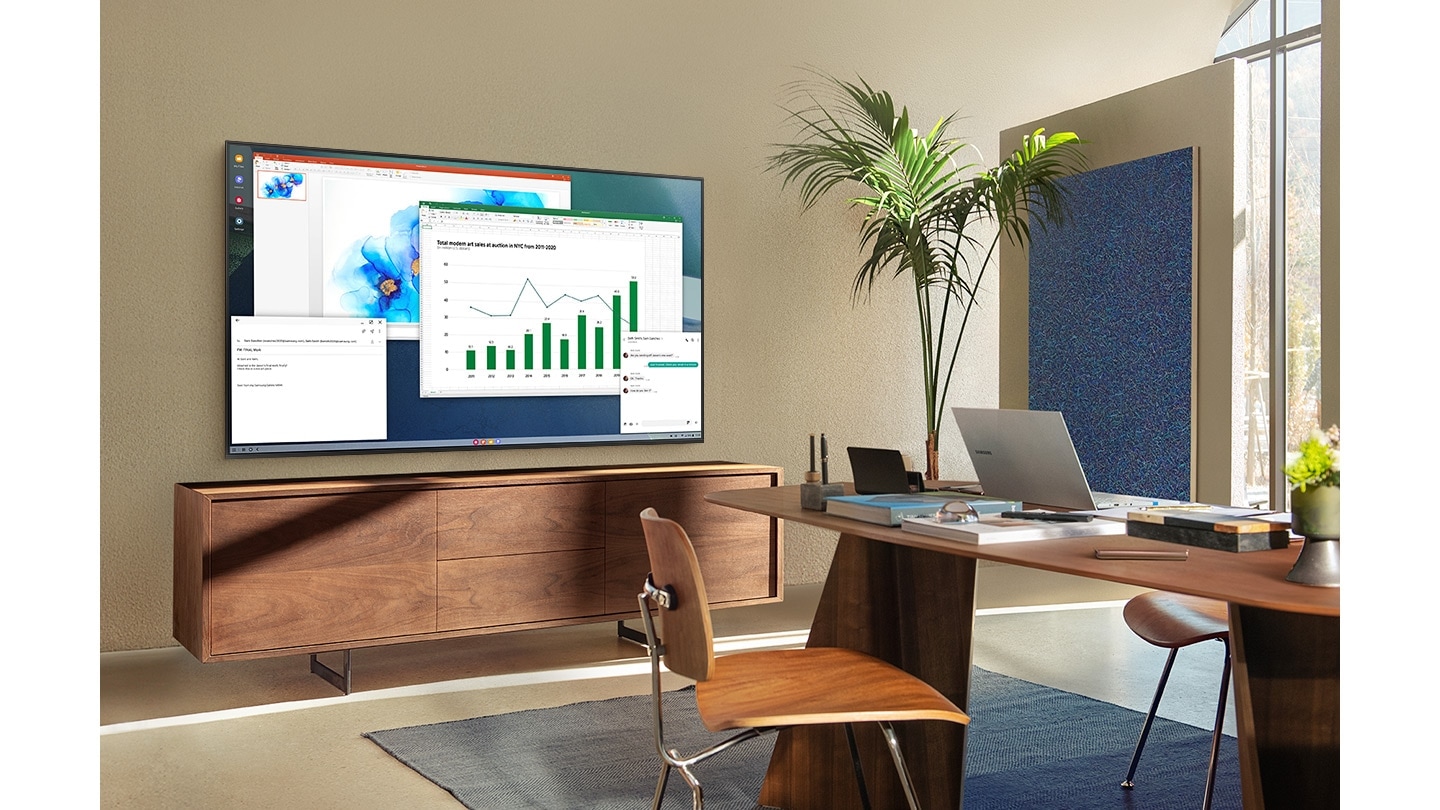 In a living room home office, QLED TV screen shows PC on TV feature which allows home TV to connect to office PC.