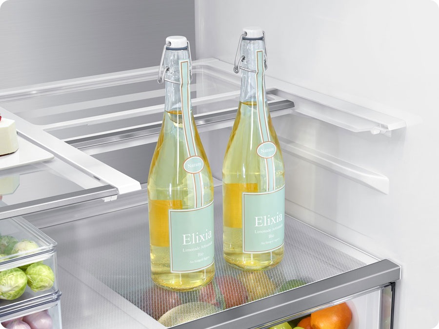 There is a closeup of a folded slide-in shelf inside the refrigerator. There are two tall glass bottles.