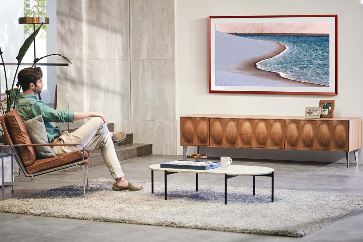 A man enjoys the ocean beach image on his living room the Frame TV.