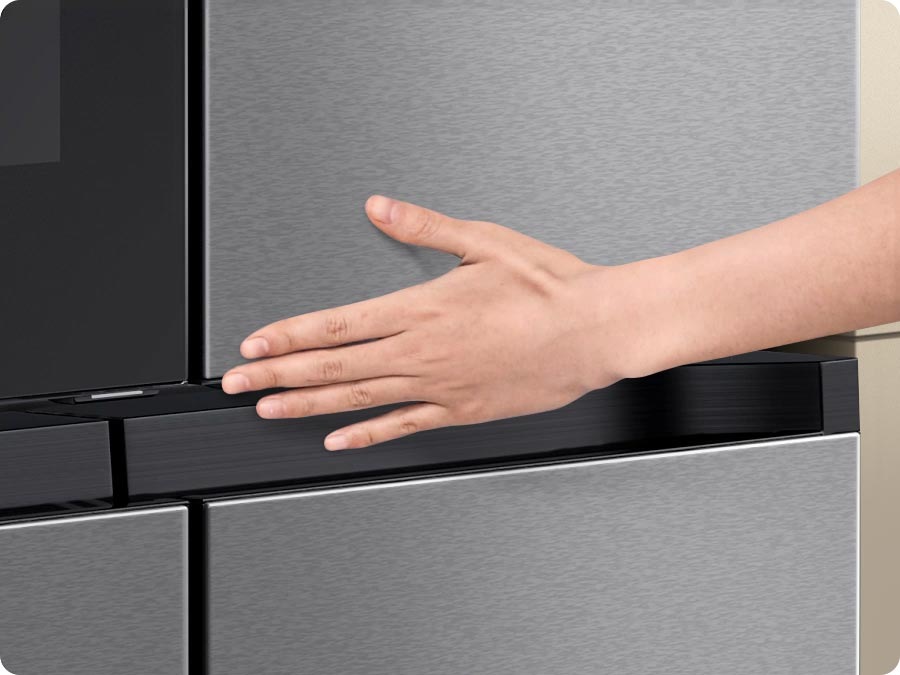 There is a close-up of the bottom corner of the top panel. A hand slightly touches the Auto Open Door's touch sensor and the door automatically opens.