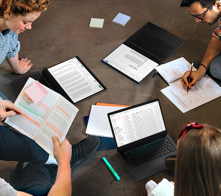 Sitting on the floor, 4 students are working on a project together. Along with physical learning materials such as a handout and a book, 3 Galaxy Chromebook Go devices are being used, each laid flat or standing upright.