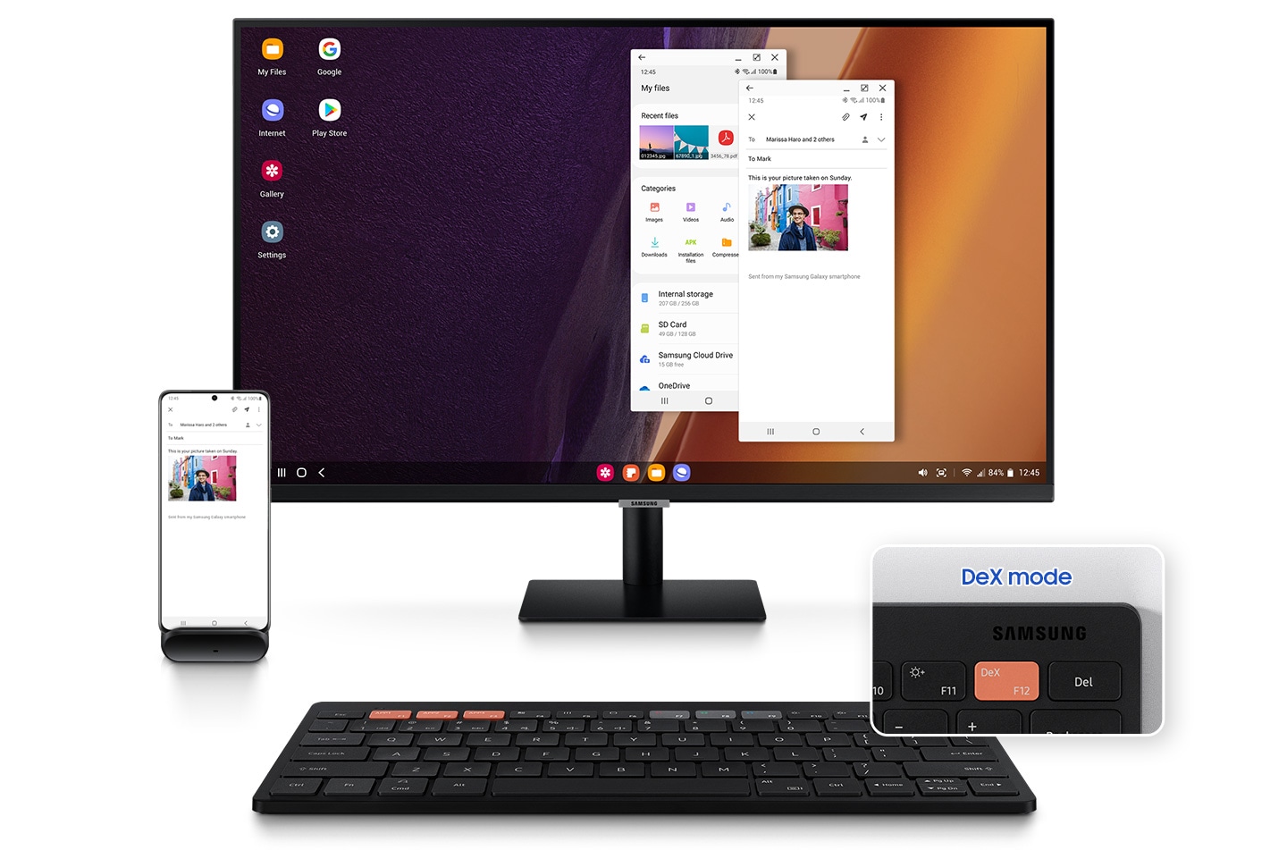 There is a black-colored Samsung Smart Keyboard Trio 500 and a monitor above the keyboard on which there are two apps that appear to be opened; one is an email app and the other one is a picture list app. Beside a monitor, there is a smartphone placed on a phone holder, where the same email app is opened. †DeX mode' key button which allows the user to access DeX mode by pressing the F12 button on the keyboard is highlighted on the bottom right side.