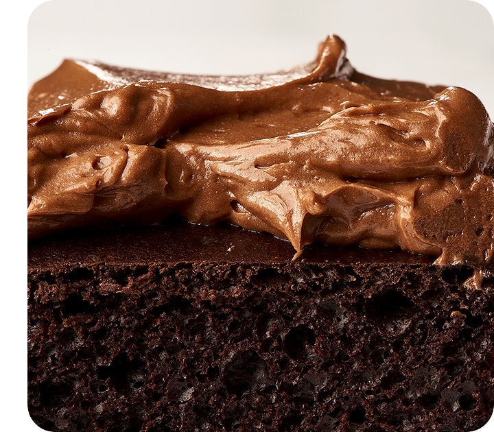 Un primo piano estremo di una fetta di torta al cioccolato, che mostra i dettagli della consistenza della torta e il vortice della glassa.