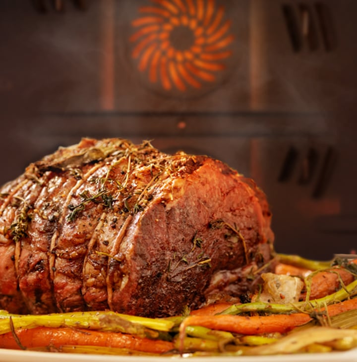 Shows a succulent joint of meat being roasted as a heated fan at the back spreads heat evenly all around the oven.
