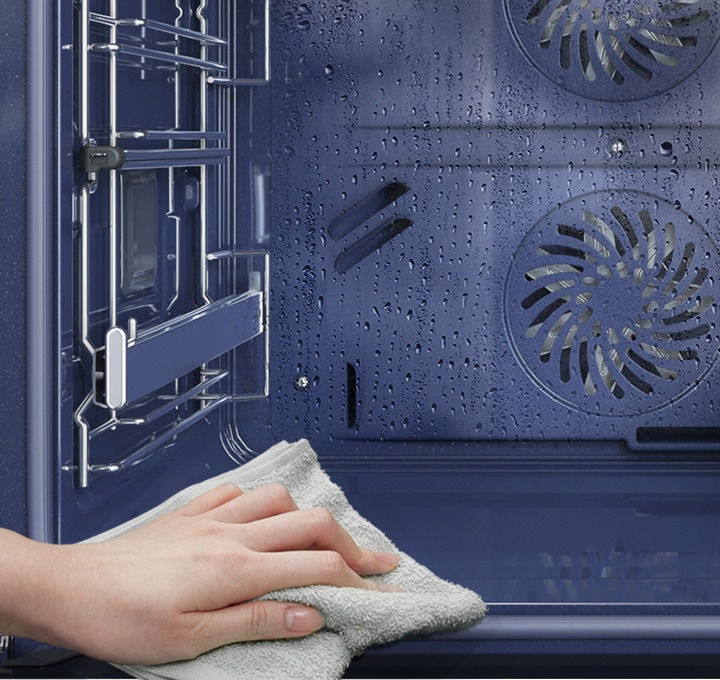 Shows the inside of the oven after Steam Cleaning, with a person wiping away any remaining residue.