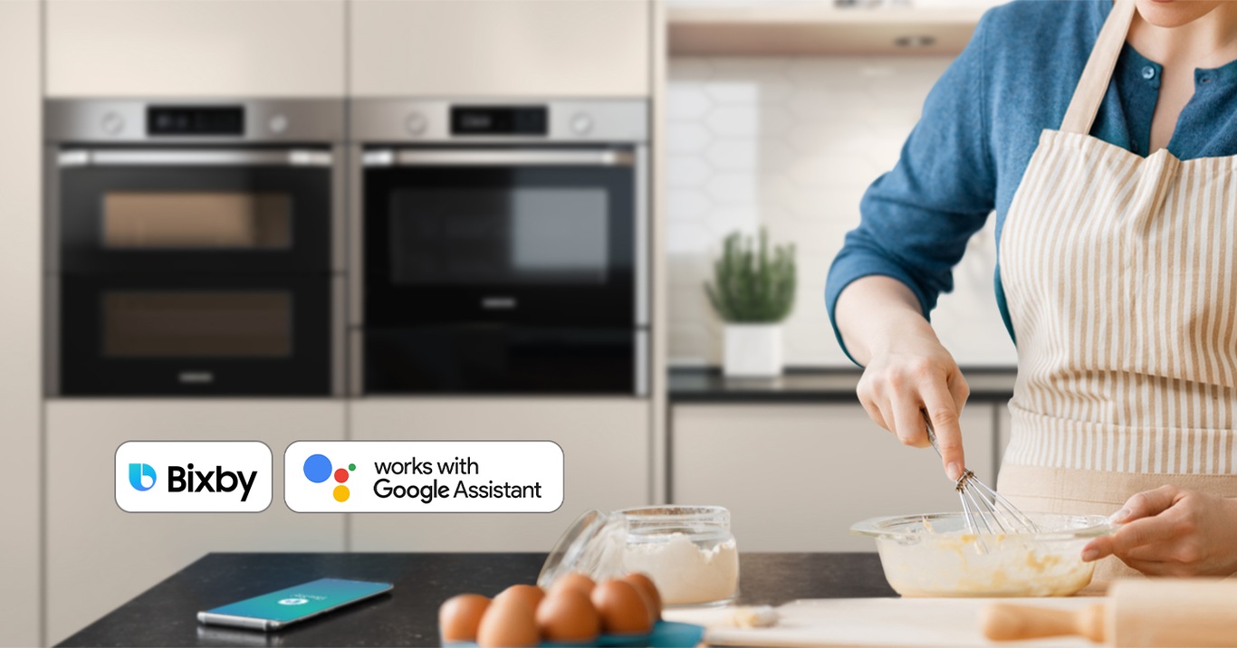 Shows a person baking while controlling the oven with their voice using a smartphone app, such as Bixby and Google Assistant.