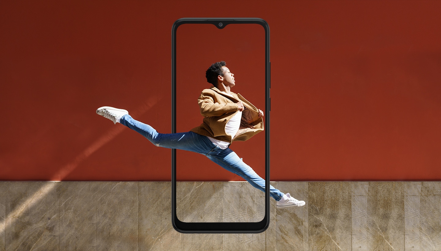 Galaxy A03 seen from the front. A man leaps across a stage with his legs outstretched, centered inside the display. His legs and the rest of the stage extend outside of the boundaries of the display.