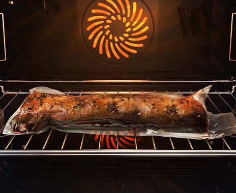 Mostra un arrosto di carne all'interno del forno, sigillato ermeticamente in un sacchetto di plastica e su una teglia di metallo, in cottura con il sistema Air Sous Vide.