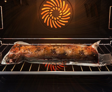 Mostra un arrosto di carne all'interno del forno, sigillato ermeticamente in un sacchetto di plastica e su una teglia di metallo, in cottura con il sistema Air Sous Vide.