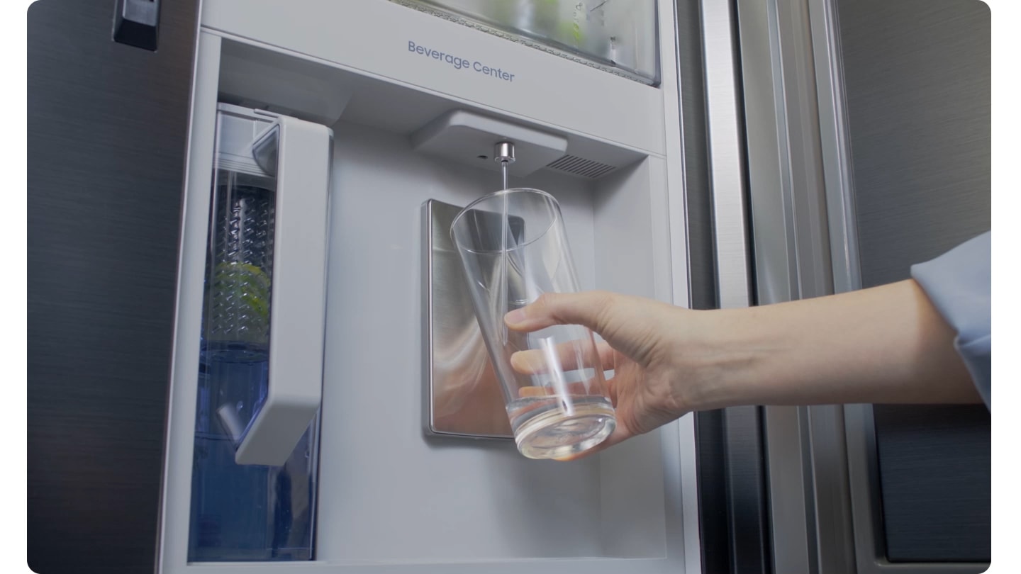 Una ragazza riempie un bicchiere d'acqua dal Beverage Center™ del suo frigorifero