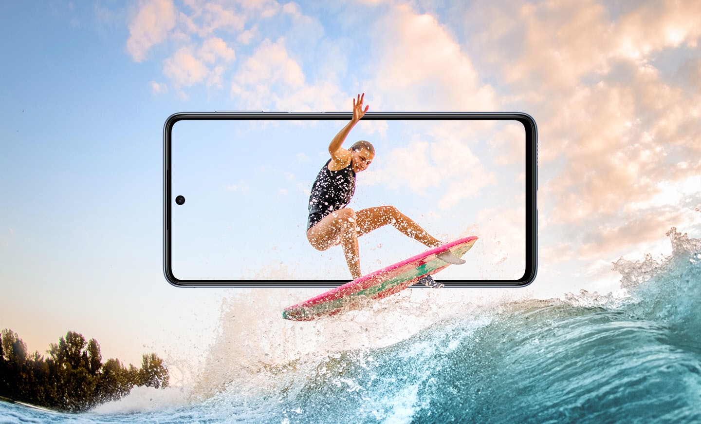A Galaxy M53 5G Super AMOLED FHD is horizontal facing forward in the center. Onscreen is a woman surfing. Her board and right hand extend beyond the frame of the display, and around it is a scene of waves and blue sky with pink clouds.