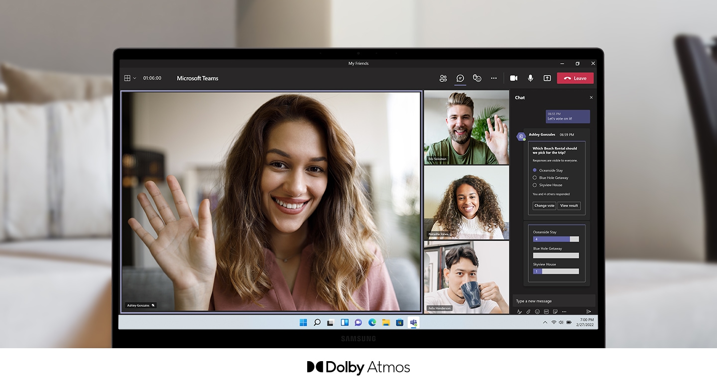 A Galaxy Book2 is facing the front with a video call taking place onscreen. On the left taking up most of the screen, a woman is smiling and waving. To her right are three other participants, two men and a woman. On the far right is a chat room. Below the PC screen is logo for Dolby Atmos.