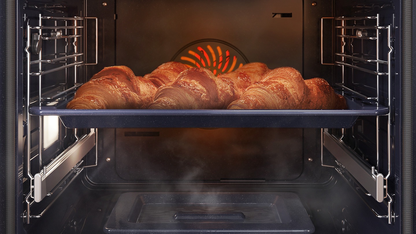  Mostra una teglia di croissant all'interno del forno in cottura con il sistema a convezione, mentre è avvolta dal vapore che sale da un'apposita teglia posta sul fondo del forno.