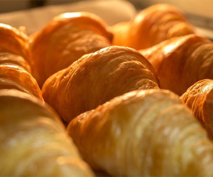 Mostra un primo piano di croissant cotti nel forno, ma mantenuti umidi con vapore utilizzando l'opzione Natural Steam.