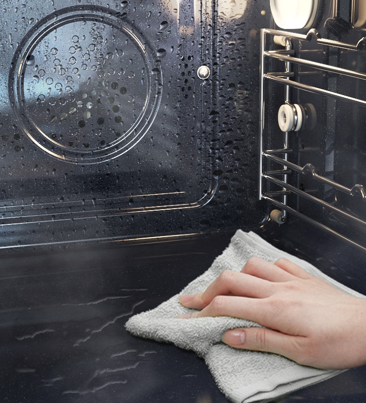 Shows the inside of the oven after Steam Cleaning, with a person wiping away any remaining residue.