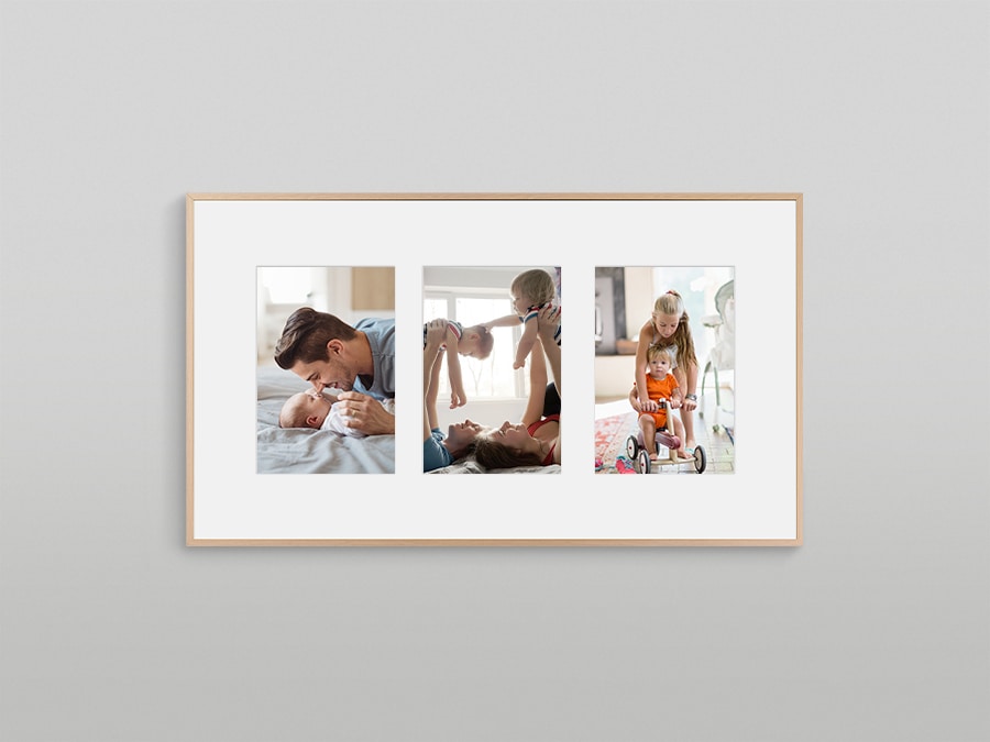 The Frame is hanging on a wall displaying 3 different types of pictures with a white matte background.