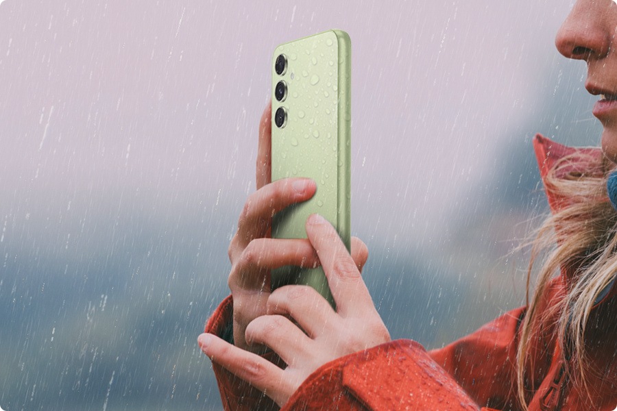 Una donna scatta una foto con un Galaxy A54 5G in Awesome Lime sotto la pioggia. 