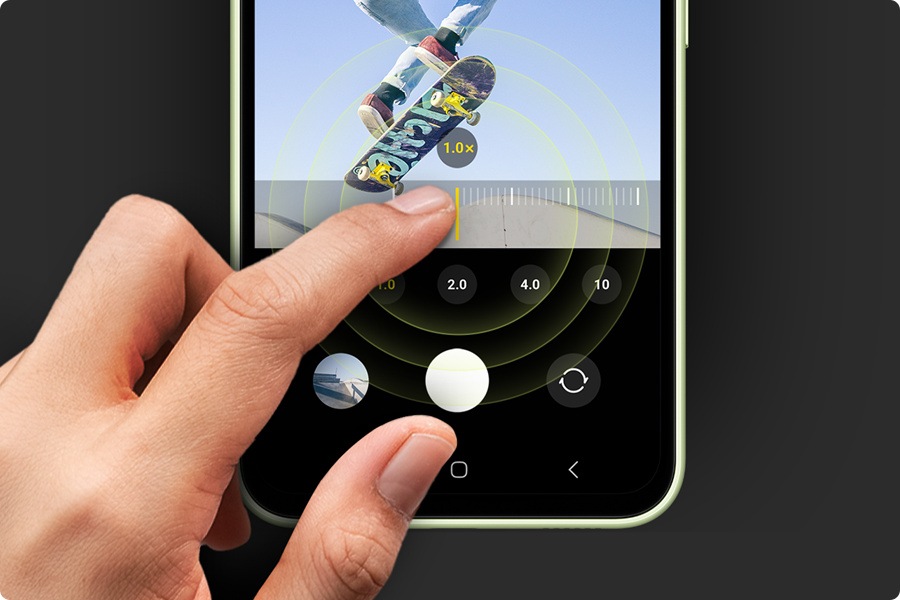 L'immagine mostra un dito che tocca lo schermo di un Galaxy A54 5G e cambia la scala di zoom della foto di uno skateboarder. 