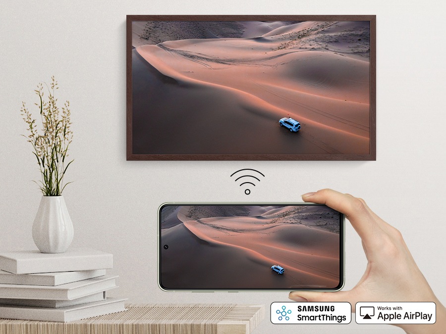 A person is holding a smartphone, which is mirroring the same content on The Frame.