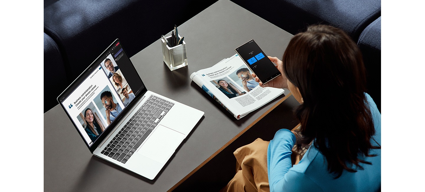 Una persona sta usando Galaxy S24 Ultra come videocamera collegata su Galaxy Book4 Pro con la finestra di videochiamata di gruppo di Microsoft Teams visualizzata sullo schermo.