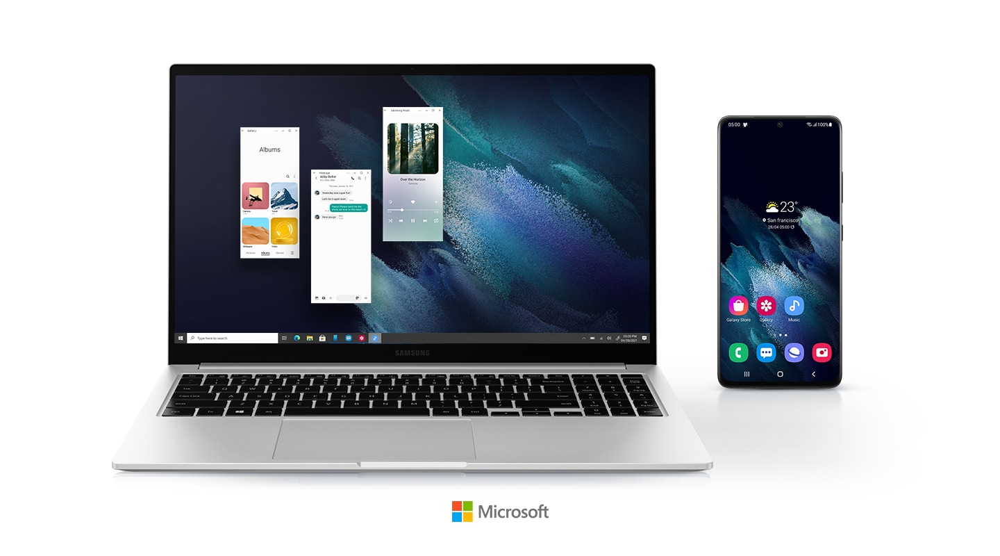 Three Android apps are being run on the Galaxy Book utilizing the Your Phone app. A mobile phone is placed right next to the laptop, showing a display with 7 app icons on it, meaning apps can be operated on laptop without using mobile phone. Microsoft logo placed at the bottom.