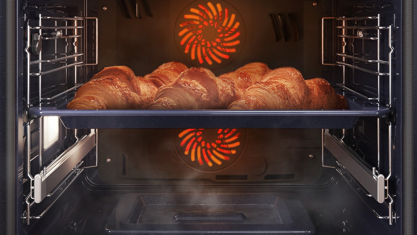 Mostra una teglia di croissant all'interno del forno in cottura con il sistema a convezione, mentre è avvolta dal vapore che sale da un'apposita teglia posta sul fondo del forno.