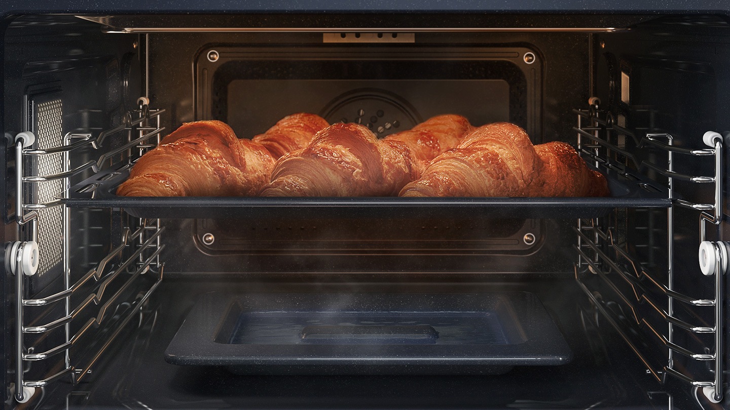  Mostra una teglia di croissant all'interno del forno in cottura con il sistema a convezione, mentre è avvolta dal vapore che sale da un'apposita teglia posta sul fondo del forno.