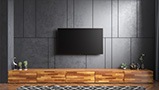Crystal UHD TV is wall-mounted against gray wall and hanging above wood-colored TV cabinet.