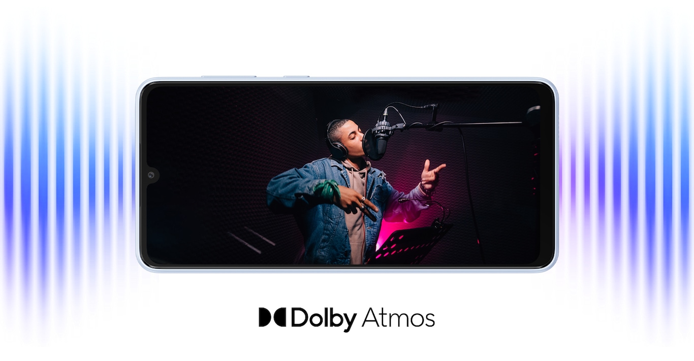 Galaxy A33 5G is laid horizontally and shows sound coming from both ends of the device. On screen, a male artist wearing headphones is singing into a studio microphone in a recording session. The Dolby Atmos logo.