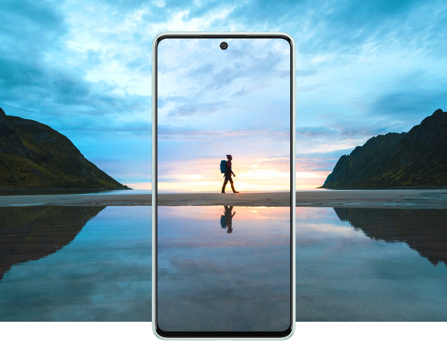 A traveler wearing a backpack is captured inside the frame of a Galaxy A73 5G device, which also shows a stunning, sunrise view which extends beyond the frame.