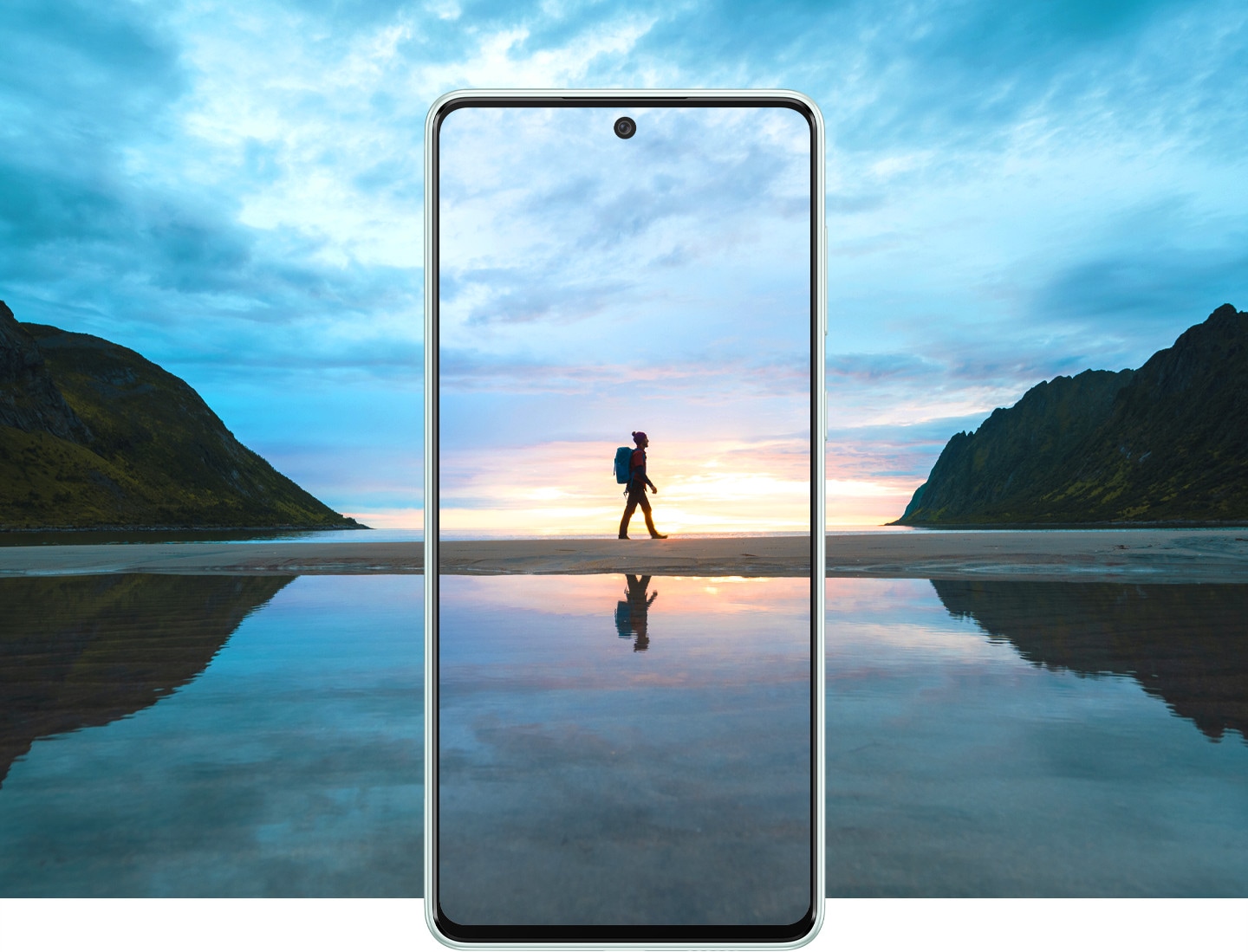 A traveler wearing a backpack is captured inside the frame of a Galaxy A73 5G device, which also shows a stunning, sunrise view which extends beyond the frame.