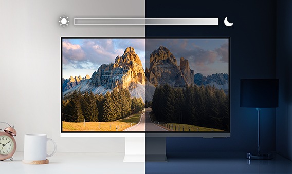 A monitor sits on top of a desk and is split into left and right sides. The left side is brightly lit while the right side is very dark. Above the screen is a slider icon with a sun on the left and a moon on the right.