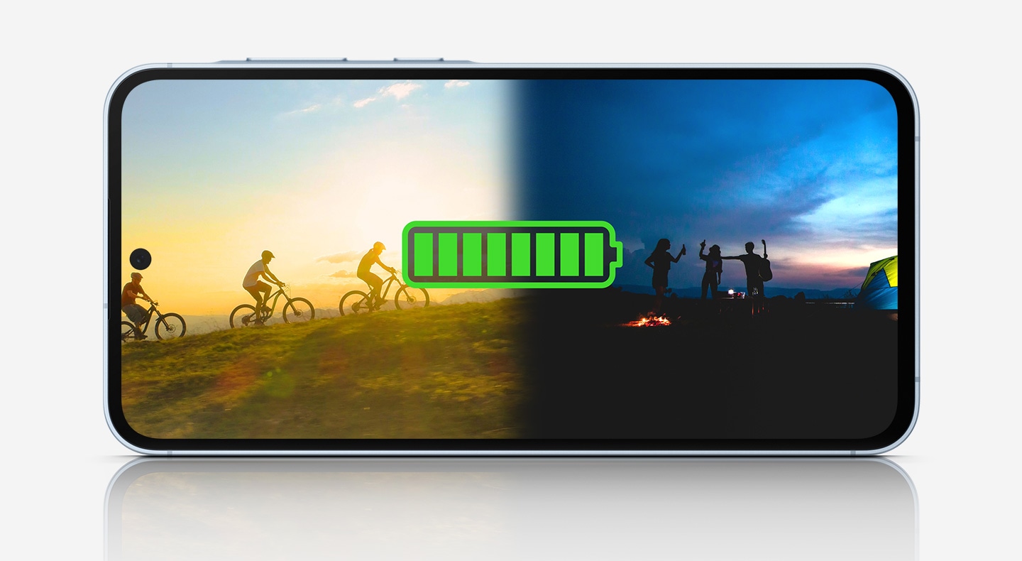 Galaxy A55 5G, на котором изображен значок батареи при полном заряде, накладывающийся на изображение людей, наслаждающихся активным отдыхом на свежем воздухе. слева велосипедисты катаются на закате, а справа группа людей собирается вечером у костра.
