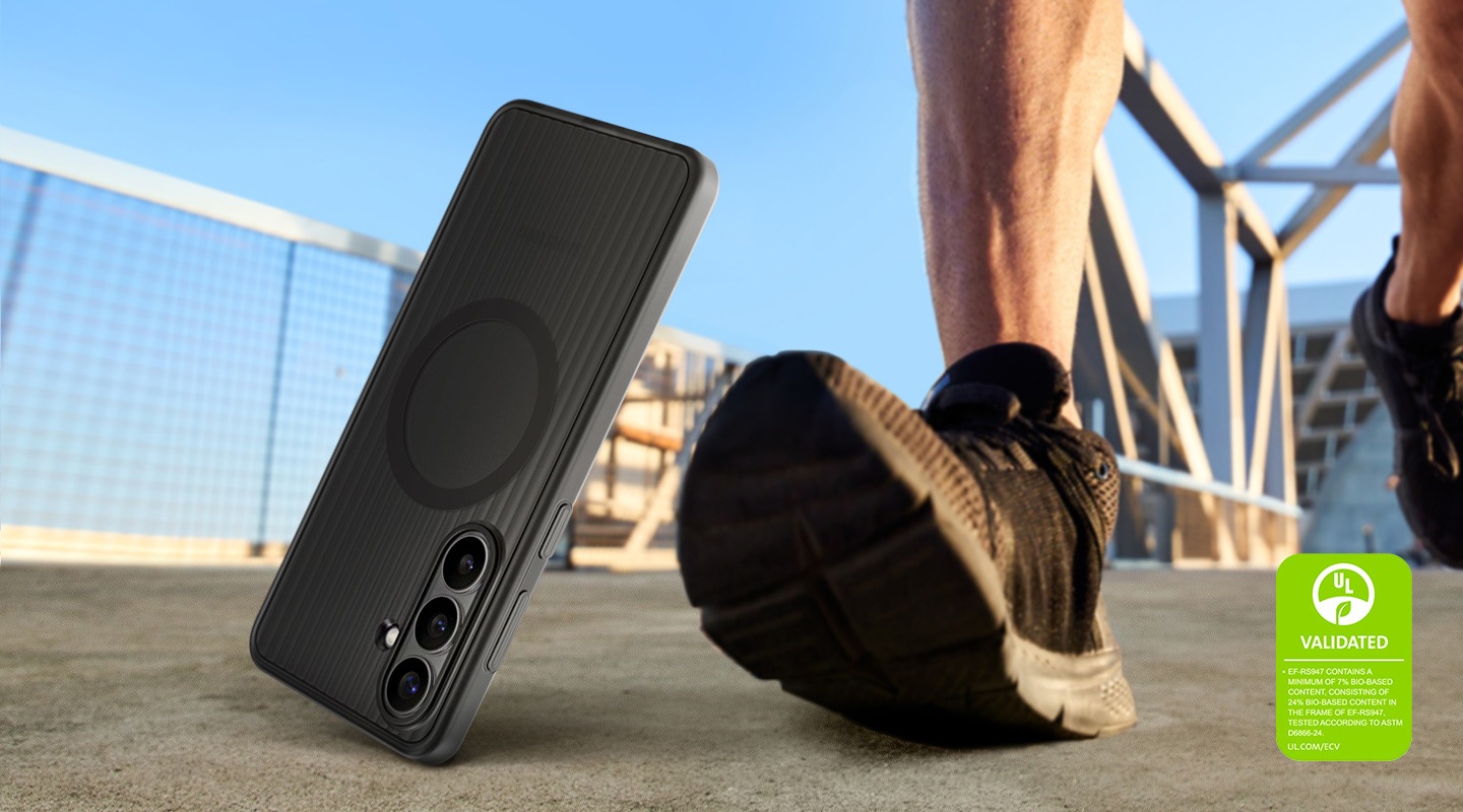 В кадре смартфон Galaxy S26+ в прочном черном магнитном чехле Rugged Magnet Case падает на землю рядом с идущим человеком, что подчеркивает износостойкость чехла и возможность его использования на природе. Демонстрируется маркировка экологической сертификации UL с текстом: &laquo;ПРОШЛО СЕРТИФИКАЦИЮ UL. ЧЕХОЛ EF-RS947 СОДЕРЖИТ НЕ МЕНЕЕ 7% БИОСЫРЬЯ, ВКЛЮЧАЯ 24% БИОСЫРЬЯ В КОРПУСЕ ЧЕХЛА EF-RS947. ПРОШЛО ИСПЫТАНИЯ ПО СТАНДАРТУ ASTM D6866-24. UL.COM/ECV&raquo;.