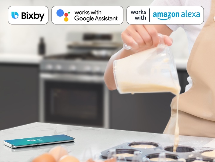Shows a person baking while controlling the oven with their voice using a smartphone app, such as Bixby and Google Assistant.