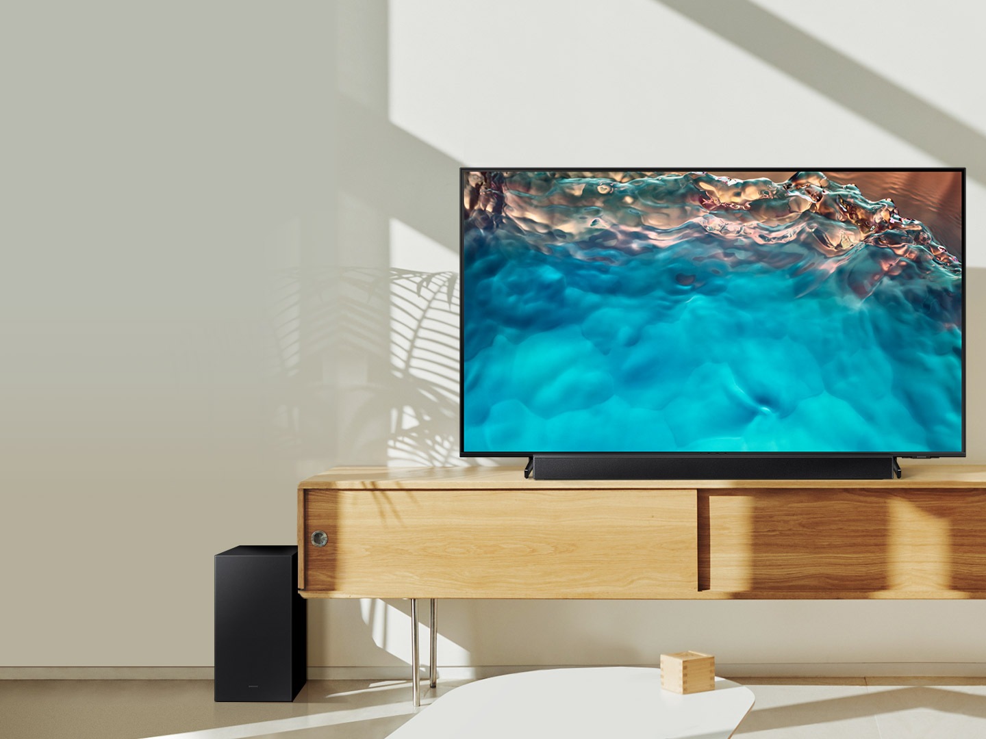 Samsung B series Soundbar and subwoofer are positioned with Crystal UHD TV on living room cabinet.