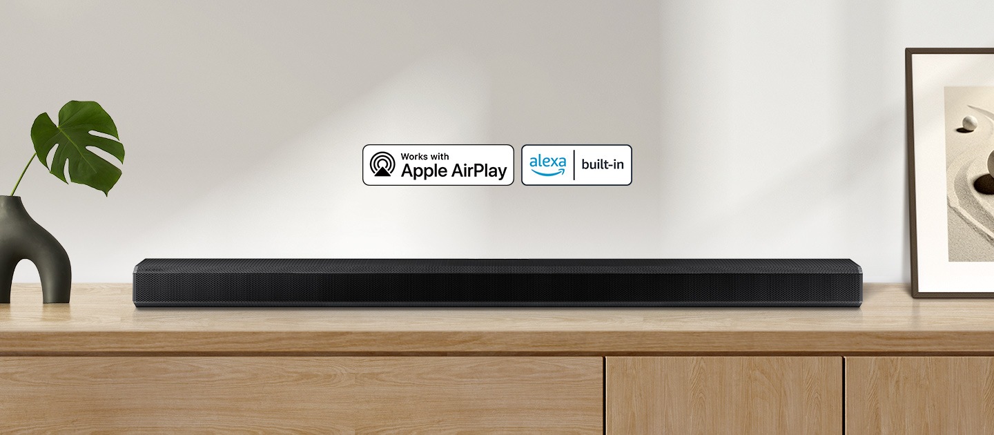 Apple AirPlay logo and Alexa Built-in logo can be seen along with Samsung Q800A soundbar which is sitting on living room cabinet.