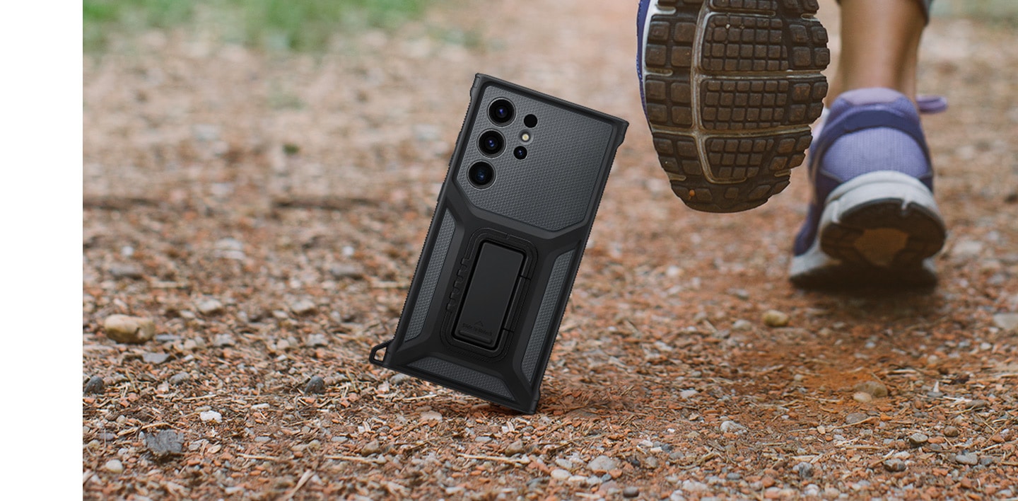 A back view of the case standing vertically next to running feet on a bumpy dirt road.