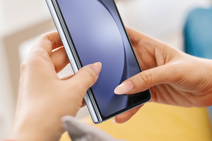 Two hands holding a Galaxy Z Fold5 device with the Front Protection Film are shown with fingernails scratching the screen to highlight the anti-scratching coating.