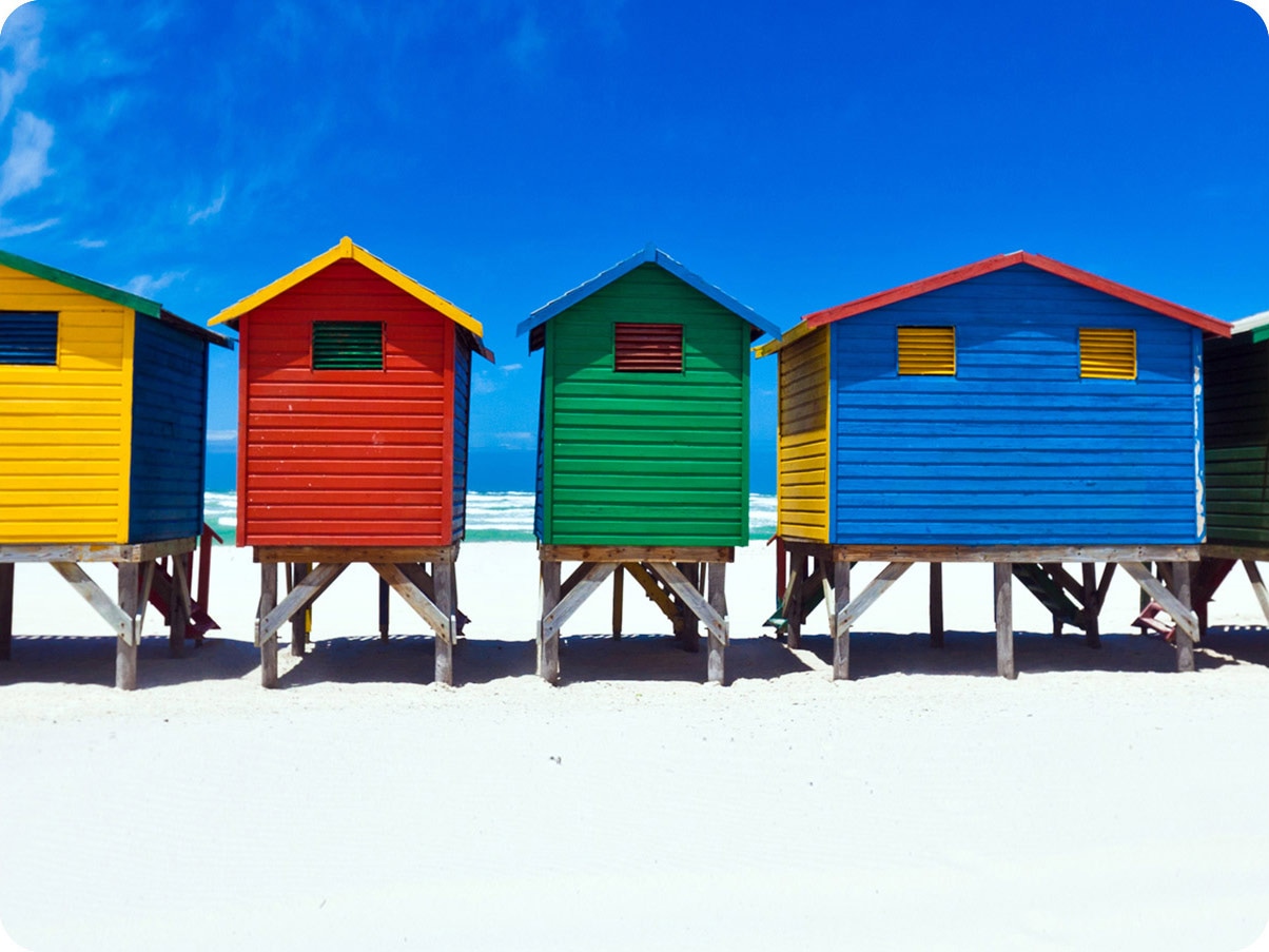 The colorful houses are lined up with the blue sky. It is a close crop shot, showing the 4 colors (yellow,red,green,blue) of houses.