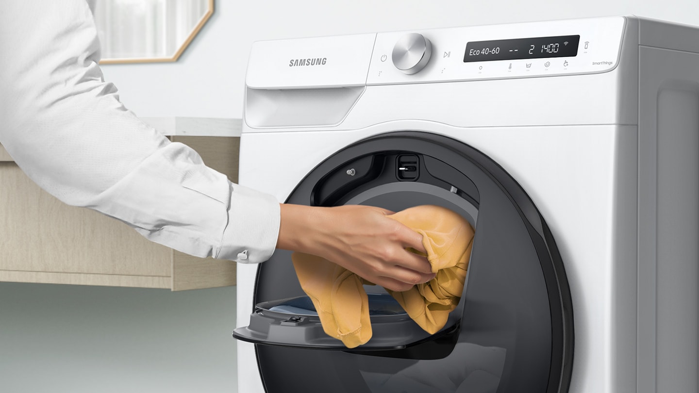 Extra laundry is added into the open Add Wash door by hand.