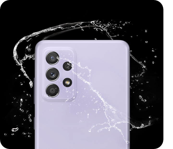 Galaxy A52 5G in Awesome Violet, seen from the rear with water splashing around it.