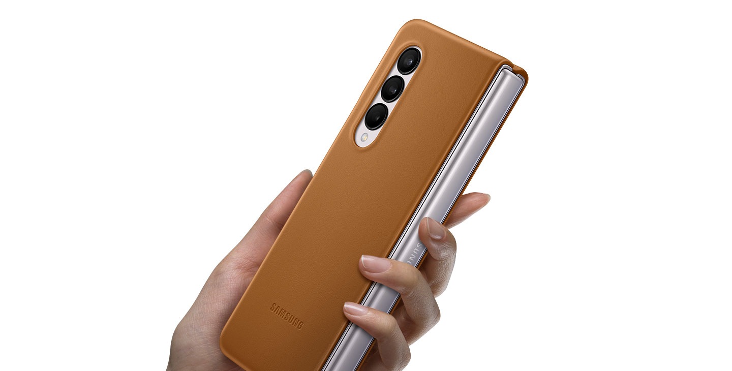 A hand holding Galaxy Z Fold3 5G folded with the Leather Cover installed.