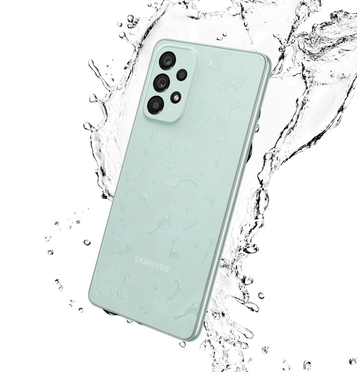 Galaxy A73 5G in Awesome Mint, seen from the rear with water splashing around it.