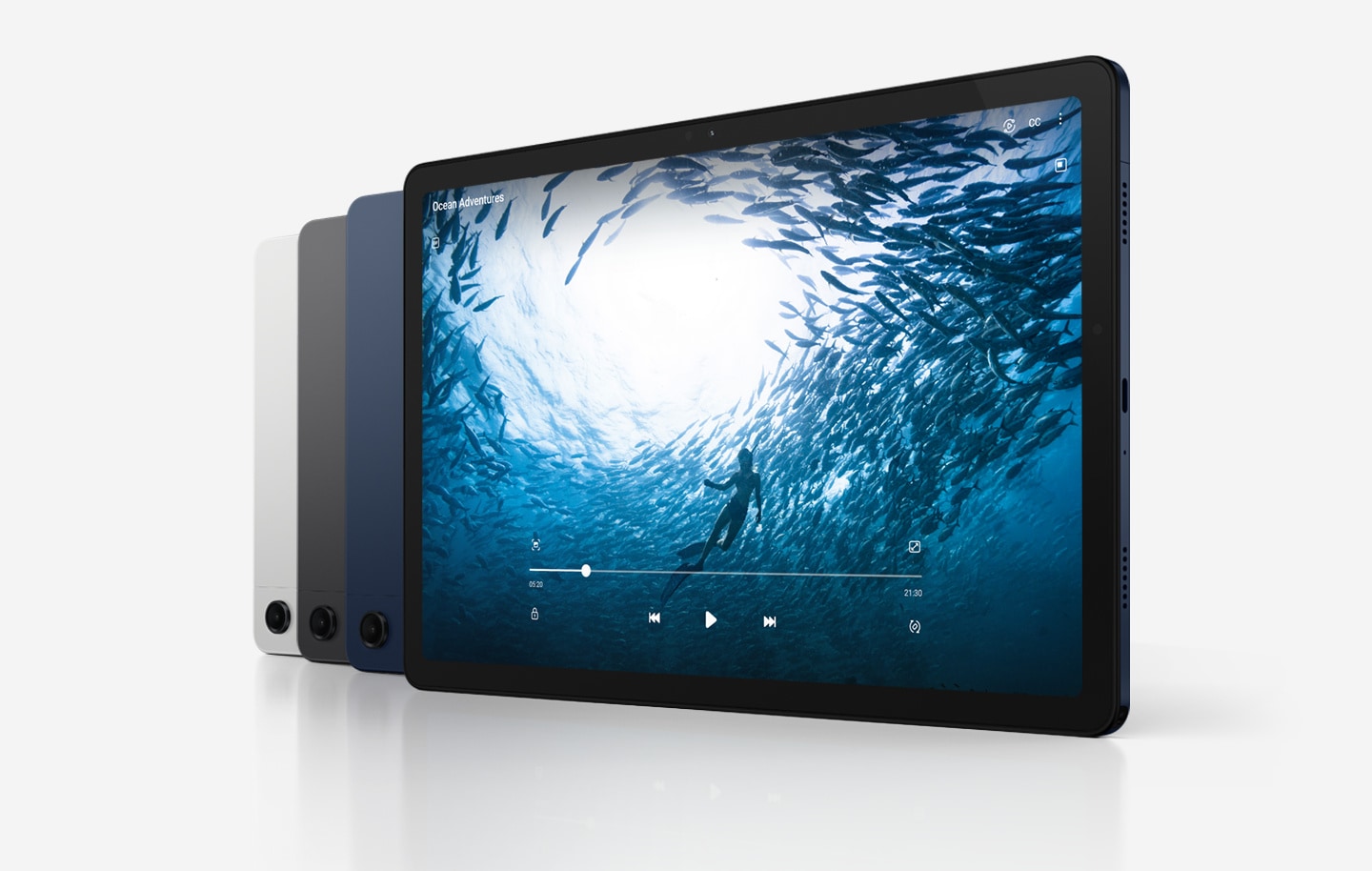 Четыре устройства Galaxy Tab A9+ расположены по диагонали.  У трех устройств задняя сторона обращена вперед, а у самого правого — экран.  Слева направо цвета устройств — Серебристый и Графит, остальные — Темно-синий.  На экране устройства справа отображается видео под названием Ocean Adventures, в котором человек плавает в океане в окружении рыб.