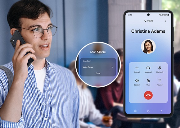 A man is talking on the phone with a loud group of friends laughing and talking behind him. To the right a Galaxy M55 5G device shows that he is talking to Christina Adams, and a pop-up next to the device shows that he is using Voice Focus to speak clearly through the chatter.